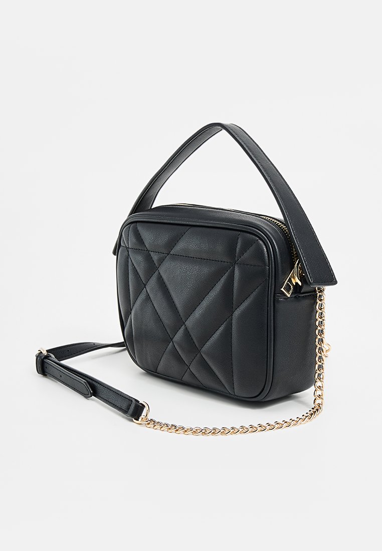 Bolso de mano de cuero negro acolchado con forma cuadrada, asa corta y una correa de cadena para el hombro desmontable. Presenta acentos en herrajes dorados.
