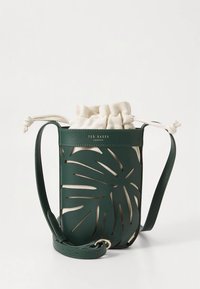 Groene leren handtas met uitgestanst bladmotief, beige canvas binnenkant met trekkoord, en verstelbare riem. Voorzien van het merklogo aan de voorkant.