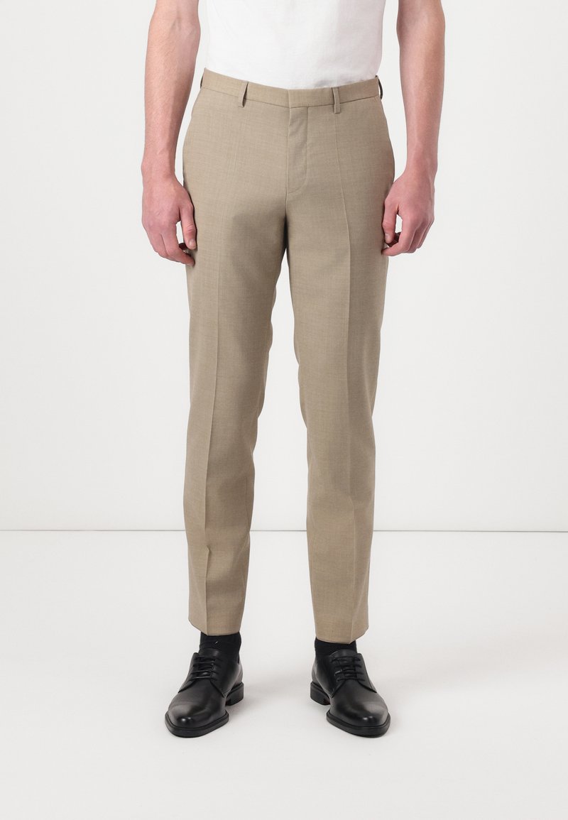 Beige tailored trousers with a flat front, slim fit design, and subtle texture. Paired with black dress shoes, standing against a light background.