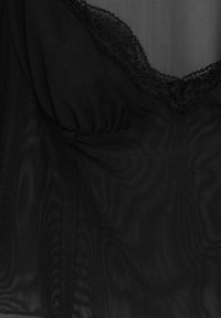 Haut en tissu mesh noir avec bordure en dentelle au niveau du col, présentant des fronces douces et une texture lisse. Détails des coutures visibles sur le côté.