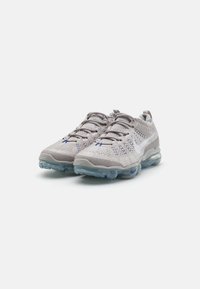 Gray athletic shoes with a mesh upper, textured detailing, and a translucent blue sole. Features laces and a rear pull tab.