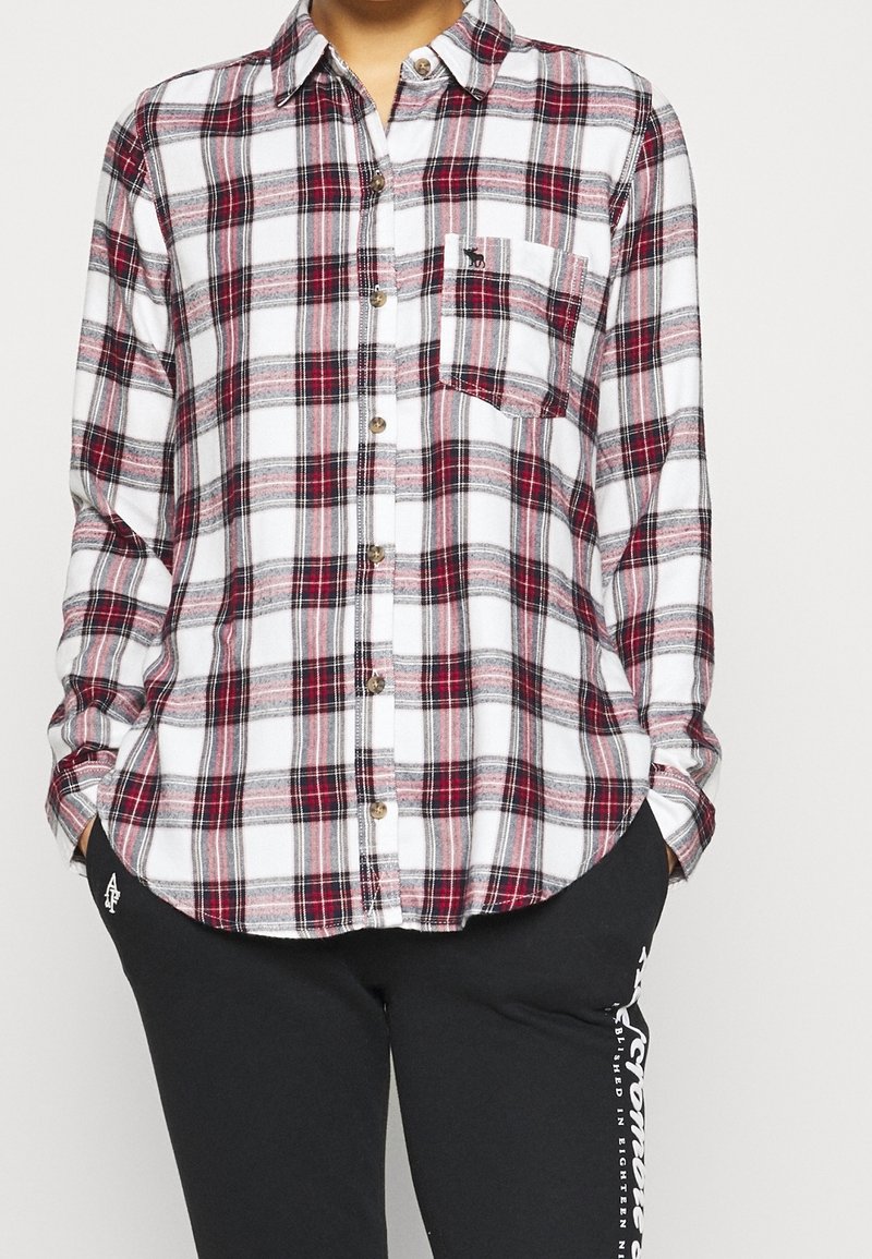 Camicia in flanella a quadri bianca, rossa e grigia. Presenta chiusura con bottoni, colletto e taschino sul petto. Tessuto morbido con vestibilità comoda.