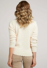 Pull crème à la finition douce et texturée, avec des poignets côtelés et un ourlet festonné. Équipé de manches trois-quarts et d'une coupe décontractée.