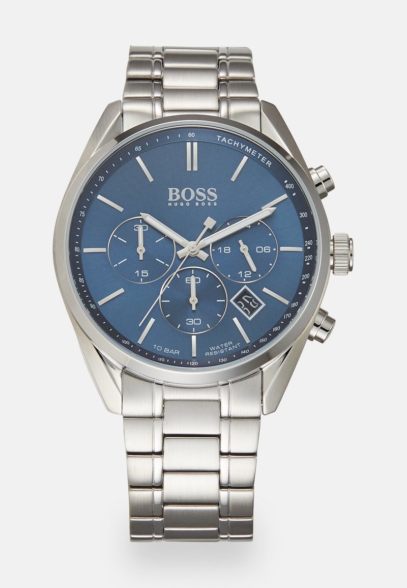 Hõbedane roostevabast terasest kell sinise analoogdialgiga, kronograafi aladialgiga, takymeetriga ja kuupäeva näidikuga. Omab metallist rihma.