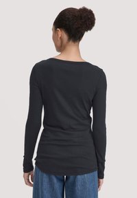 Zwarte, lange mouwen top met een ronde halslijn, aansluitende silhoette en zachte textuur, gecombineerd met losse, blauwe denim broeken.