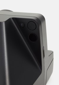 Black electronic device with a textured surface, featuring a power button, a charging port, and a lightning bolt symbol.