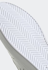 Vit sneakersula med ett zigzagmönster, med en texturerad kant och platt design. Materialet verkar slätt och gummilikt.