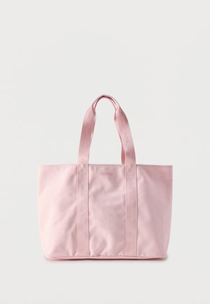 Sac fourre-tout rose clair avec poignées de marque et logo "HUGO" subtil sur le devant, fond uni.