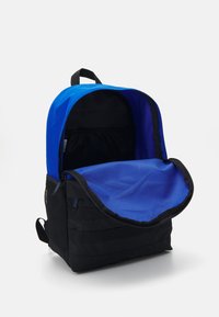 Mochila preta e azul com um design curvado, apresentando uma pega superior, fecho com zíper e bolso interior em malha. O interior é de tecido azul.