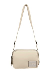 Beige crossover bag med en glat, polstret tekstur, lynlåslukning og et logo-patch. Har en tynd, justerbar rem.