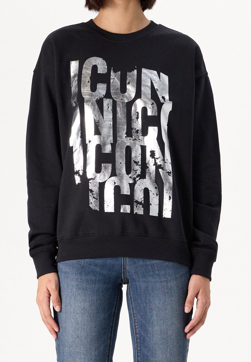 Sudadera negra con gráfico de texto plateado desgastado que dice "ICONIC." Cuenta con mangas largas y cuello redondo. El estilo es de corte relajado.