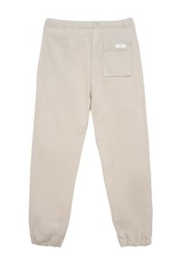 Beżowe joggery zwężane z elastycznym paskiem w talii, żebrowanymi mankietami i jedną tylną kieszenią naszywaną. Miękka tkanina o gładkiej teksturze.