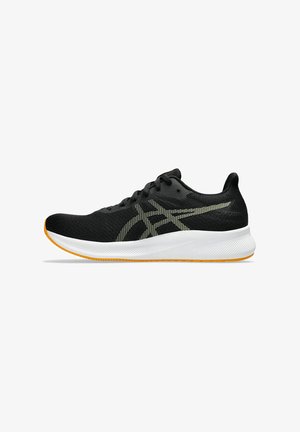 Baskets de sport noires avec une tige en maille, des accents dorés réfléchissants, et une semelle blanche rembourrée avec une semelle extérieure orange.
