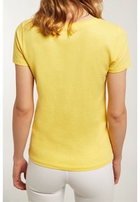 Żółta koszulka z krótkim rękawem wykonana z miękkiej bawełny. Posiada okrągły dekolt i gładką fakturę oraz dopasowany krój.