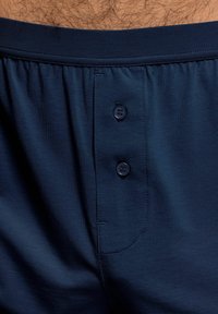 Námořnické modré boxerské šortky s hladkým, měkkým povrchem, se zvýšeným pasem a dvěma knoflíky na přední straně pro zapínání.