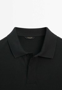 Polo noir à manches courtes avec un col côtelé et une patte de boutonnage à deux boutons, avec une petite étiquette cousue à l'encolure.