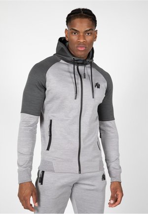 Grijze en donkergrijze zip-up hoodie met zwarte accenten en logo. Voorzien van een capuchon, voorzakken en aansluitende mouwen. Gemaakt van gestructureerd materiaal.