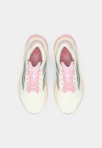 Ελαφριά αθλητικά παπούτσια με εκρού επάνω μέρος, ροζ λεπτομέρειες και γκρι ρίγες. Διαθέτουν στρογγυλά κορδόνια, διάτρητη υφή και μαλακές σόλες.