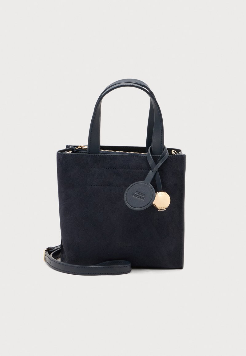 Sac fourre-tout en daim noir avec deux poignées supérieures, une bandoulière amovible et deux breloques décoratives attachées à une poignée.