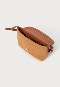 Tan suede bag with a smooth texture, featuring a single button closure and an interior pocket, designed with a rectangular shape.