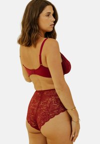 Ensemble de soutien-gorge en dentelle rouge et de culotte taille haute avec motifs floraux, bretelles réglables et bordure en feston. Fini lisse, matériau léger.