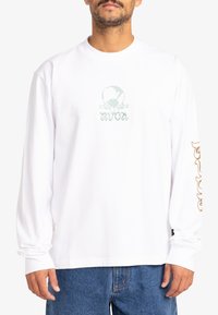 Witte longsleeve t-shirt van katoen, met een zachtgroen grafisch logo op de voorkant en beige tekst op de linkermouw.