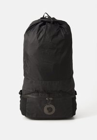 Zaino con cordino nero realizzato in tessuto resistente con una texture liscia. Presenta una tasca frontale con zip e un accentuazione decorativa a forma di logo circolare.