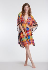 Värviline mustriline kaftan oranži, sinise ja kollasega, laiad varrukad, V-kaelus ning kaunid tikandid kaela ümber.