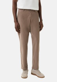 Beige bomuldsbukser med en afslappet pasform, flad front og sidelommer. Bæres med lysefarvede sneakers for et afslappet look.