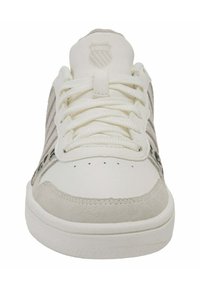 Bílé tenisky s šedými semišovými akcenty a texturovanými bočními panely. Obsahují ploché tkaničky, perforace na špičce a embosované logo na jazyku.