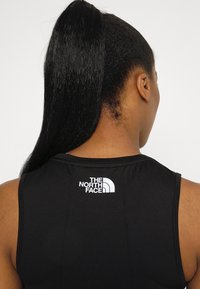 Black sleeveless athletic top featuring a rounded neckline and white logo "THE NORTH FACE" on the upper back. Smooth fabric texture.