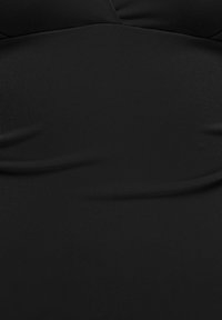 Gros plan d’un vêtement en tissu noir avec un col en V légèrement marqué et une texture lisse, montrant de petits plis.