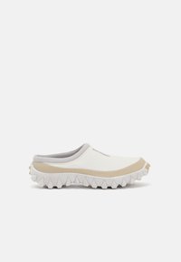 Balti slip-on batai su tekstūruotu paviršiumi, smėlio spalvos akcentais ir storu, dantytu padu. Yra paminkštintas apykaklės kraštas ir logotipo detalė.