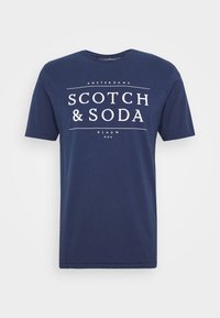 Granatowa bawełniana koszulka z krótkim rękawem z białym graficznym nadrukiem tekstowym z napisem "SCOTCH & SODA" oraz "AMSTERDAMS" z przodu. Okrągły dekolt.