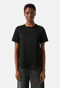 Schwarzes T-Shirt mit kurzen Ärmeln und Rundhalsausschnitt, aus glattem Stoff, mit lockerem Schnitt und minimalistischem Design.