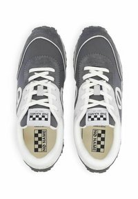 Zapatillas grises y blancas con parte superior texturizada, puntera redonda, cordones blancos y etiqueta a cuadros. Cuentan con suela de goma y un diseño simple.