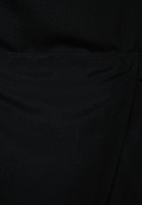 Tissu textile noir avec une texture lisse, affichant un subtil éclat. Le matériau semble léger avec un design sans embellissement.