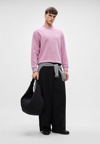 Sudadera rosa claro, pantalones negros holgados, cinturón a rayas blancas y negras, y un bolso negro de hombro, con texturas suaves y un diseño casual.