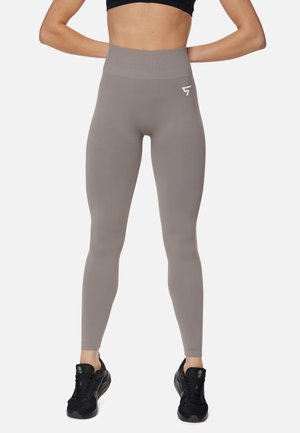 High-waisted leggings in taupe, made from stretchy fabric. Features a smooth texture and a white logo detail on the waistband.