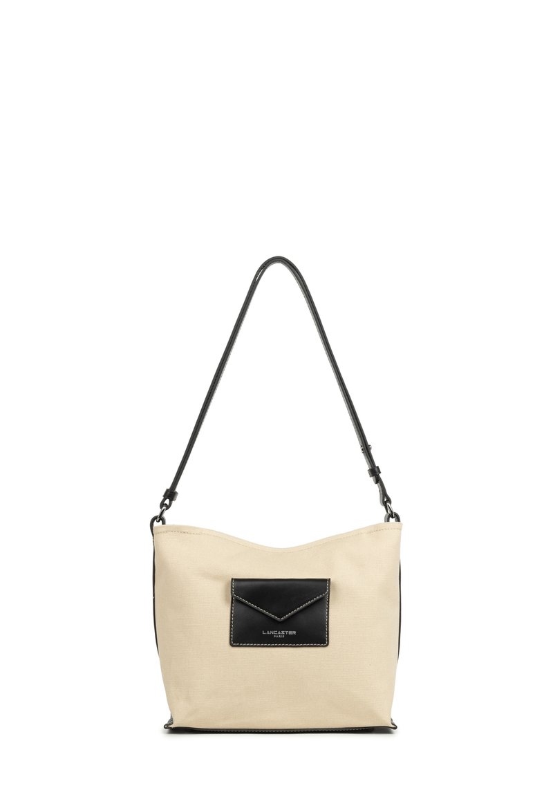 Borsa a spalla in canvas beige con tasca in pelle nera, forma arrotondata e una sola tracolla regolabile. Presenti dettagli di cucitura a contrasto.