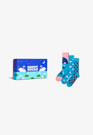 Dárková krabička vedle tří barevných ponožek s motivy labutí, vodních lilijí, puntíkatého vzoru a noční oblohy na bílém pozadí.