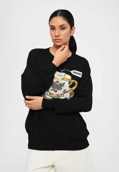 Schwarzer Strickpullover mit einem bunten Teetassendesign und floralen Akzenten. Rippenbündchen und Saum, lässige Passform. Markenlabel sichtbar.
