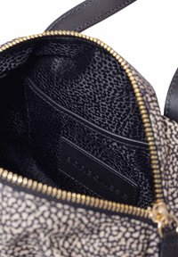 Nahaufnahme eines offenen Reißverschlussbeutels mit schwarzem, strukturiertem Innenfutter und Innentasche, die ein Borbonese Markenschild im Inneren zeigt.