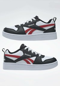 Baskets noir et blanc avec des accents rouges, dotées d'un dessus synthétique lisse, d'un système de laçage, d'un col rembourré et d'une semelle en caoutchouc blanche.