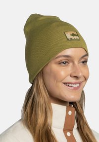 Green ribbed beanie hat with a patch featuring mountain and sun design. Soft texture, fitted shape, suitable for casual wear in cooler weather.