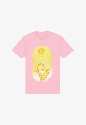 Růžové tričko s žlutým medvědem, který má na břiše sluneční emblém, obklopeným designem slunečního paprsku nahoře.