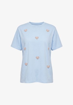 Lichtblauw T-shirt met korte mouwen en negen roze hartvormige patches, elk versierd met een klein strikje, op de voorkant geplaatst.