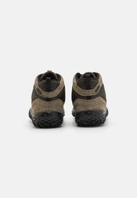 Zapatos marrones y negros con parte superior de ante y malla, diseño de tobillo bajo y suela de goma con un patrón texturizado.