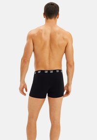 I boxer neri presentano un tessuto morbido ed elastico con una fascia larga in vita che mostra il logo "CR7" in bianco. Il design è elegante e minimalista.