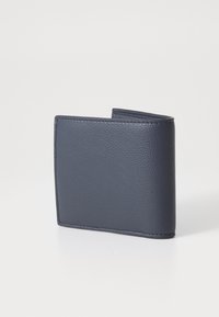 Námornícky modrá kožená peňaženka s textúrovaným povrchom, dvojitý design a kontrastnými stehom. Kompaktný tvar bez viditeľných kovových prvkov.